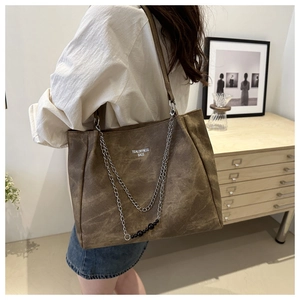 Detail of vintage brown tote bag with metal chain strap and Tidal Dryness printed text