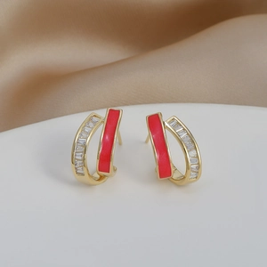 Detail of gold earrings with red enamel inlay and row of clear baguette zircon stones