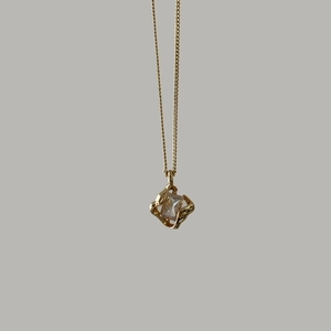 Macro detail of 18k gold plated necklace featuring square zircon in an irregular frame