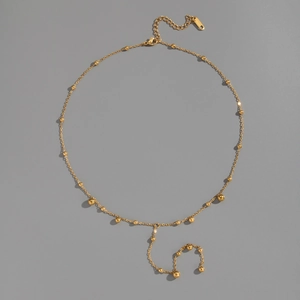 Detail of 18K gold stainless steel Y-shaped necklace with round beads on gray background