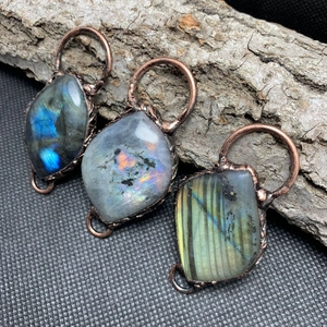 Detailed macro view of three iridescent labradorite pendants in vintage bronze wire wrap