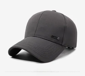 Detail of dark grey baseball cap featuring metal brand plaque and structured twill fabric