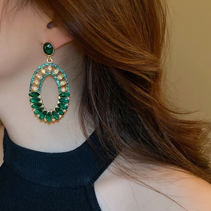 Detail of vintage gold-tone earrings with emerald green crystals and aurora borealis accents