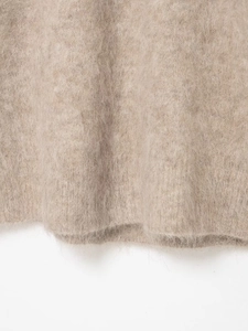 Macro detail of soft cream alpaca knit fabric showing fluffy long-pile texture and hem