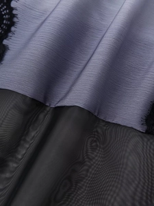 Dettaglio del tessuto plissettato malva con mesh nero e bordo in pizzo fine