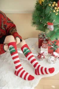 Macro detail of red and white striped coral fleece Christmas socks with festive tree motif