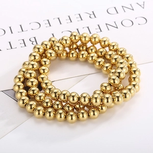 Close-up of three polished gold beaded elastic bracelets set on decorative card