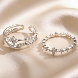Macro shot of silver multi-layer rings with clover charms on premium silk fabric