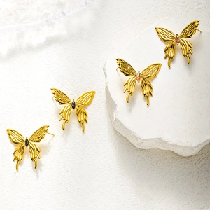 Elegant gold butterfly stud earrings with pink and black stones on white stone base