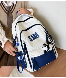 Detail of blue and white vintage backpack showing side buckle and cute panda plush charm
