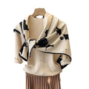 Elegant 90x90cm beige floral silk scarf with black leaf print on a wooden hanger