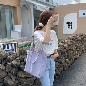 Foto callejera de un bolso tote de lona morado combinado con un estilo informal