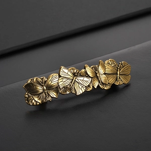 Haarklammer in Vintage-Gold mit Schmetterlingsmotiv und feiner Textur auf dunklem Grund