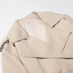 Dettaglio del colletto a rever del trench beige e design della spallina