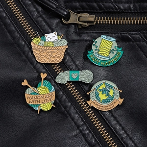 Detail of five cute cat and knitting enamel pins on a black leather jacket texture