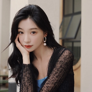 Outdoor model wearing geometric golden hoop earrings with elegant white pearl drops