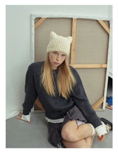 Detailed knit texture of a beige cat ear beanie with delicate ribbon bow decoration