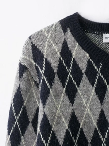 Detailed close-up of V-neck knitted sweater with classic black grey and white argyle pattern