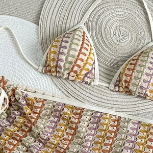 Détail macro du bikini bohème en crochet à rayures colorées sur un chapeau de paille