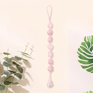 Macro shot of natural pink crystal raw stone in handmade woven hanging car decoration