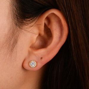 Classic gold round stud earrings with halo cubic zirconia stones on female model