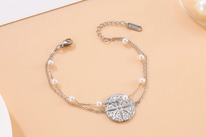 Detail of double-layer stainless steel bracelet with white pearls and star pendant
