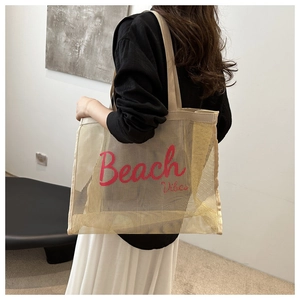 Detail of large mesh tote bag with Beach Vibes text shown on model in a minimalist room