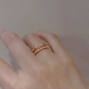 Three-piece layered gold ring set with cubic zirconia and pearls on hand