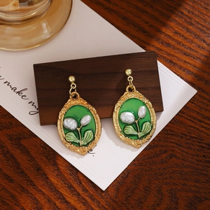 Detailed view of French vintage green oval cameo earrings with white floral pearl accents