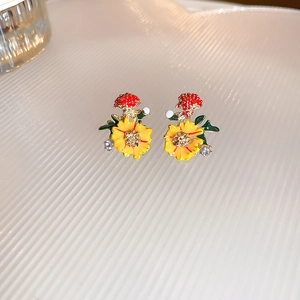 Detail of sweet floral stud earrings with red mushroom and yellow daisy in gold finish