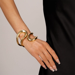 Close-up of chunky gold irregular geometric bangle on wrist with black silk texture
