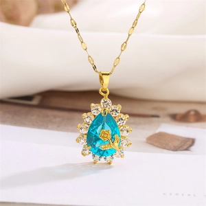 Macro detail of teardrop blue gemstone pendant with gold flower and crystal inlay