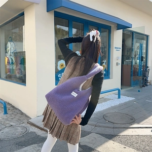 Close-up of a purple sherpa fleece tote bag with a white minimalist label on the side