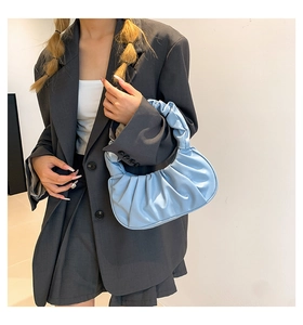 Close-up of a light blue pleated cloud bag styled with a grey blazer and skirt