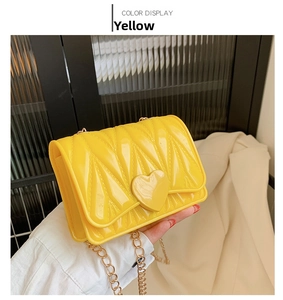 Detail of yellow silicone heart bag with radial quilted texture and gold chain strap