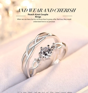 Primo piano di anelli intrecciati in argento con pietre di zircone in scatola di velluto