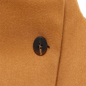 Detailed close-up of camel wool fabric texture and tortoiseshell buttons on a jacket