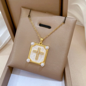 Macro detail of gold cross necklace with pearl corners and iridescent mother-of-pearl base