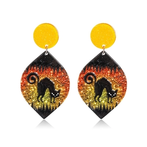 Macro detail of Halloween earrings with black cat silhouette on orange glitter acrylic background