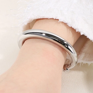 Gros plan du bracelet jonc argenté en forme de C au poignet avec manche texturée