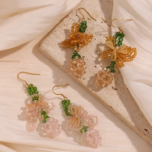 Macro detail of hand-woven pink and orange beaded floral earrings on silk fabric