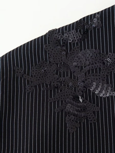 Vue macro détaillée de la broderie fleurie à paillettes noires sur tissu rayé