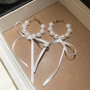 Elegant French style pearl hoop earrings decorated with delicate white ribbon bow accents