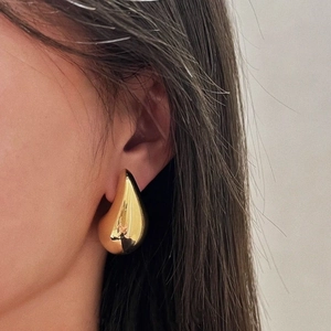 Close-up of oversized gold waterdrop earrings worn by a model for a chic style