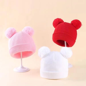 Close-up of knit winter hats with double pom-poms in pink, red and white colors