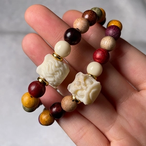 Macro detail of multi-color wooden Buddhist beads featuring a white mythical beast charm