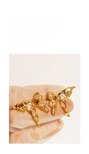 Detail of gold butterfly earrings with liquid metal texture and clear zircon stones