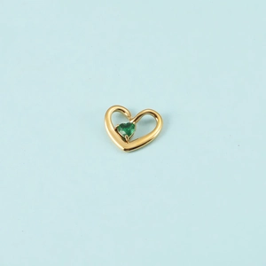 Vue détaillée d'un pendentif en forme de cœur doré avec une gemme de cœur verte
