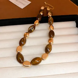 Maillard-style resin amber oval necklace with golden beads on velvet display tray