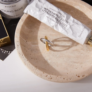 Detailed view of bicolor gold and silver interlocking rings on marble tray display